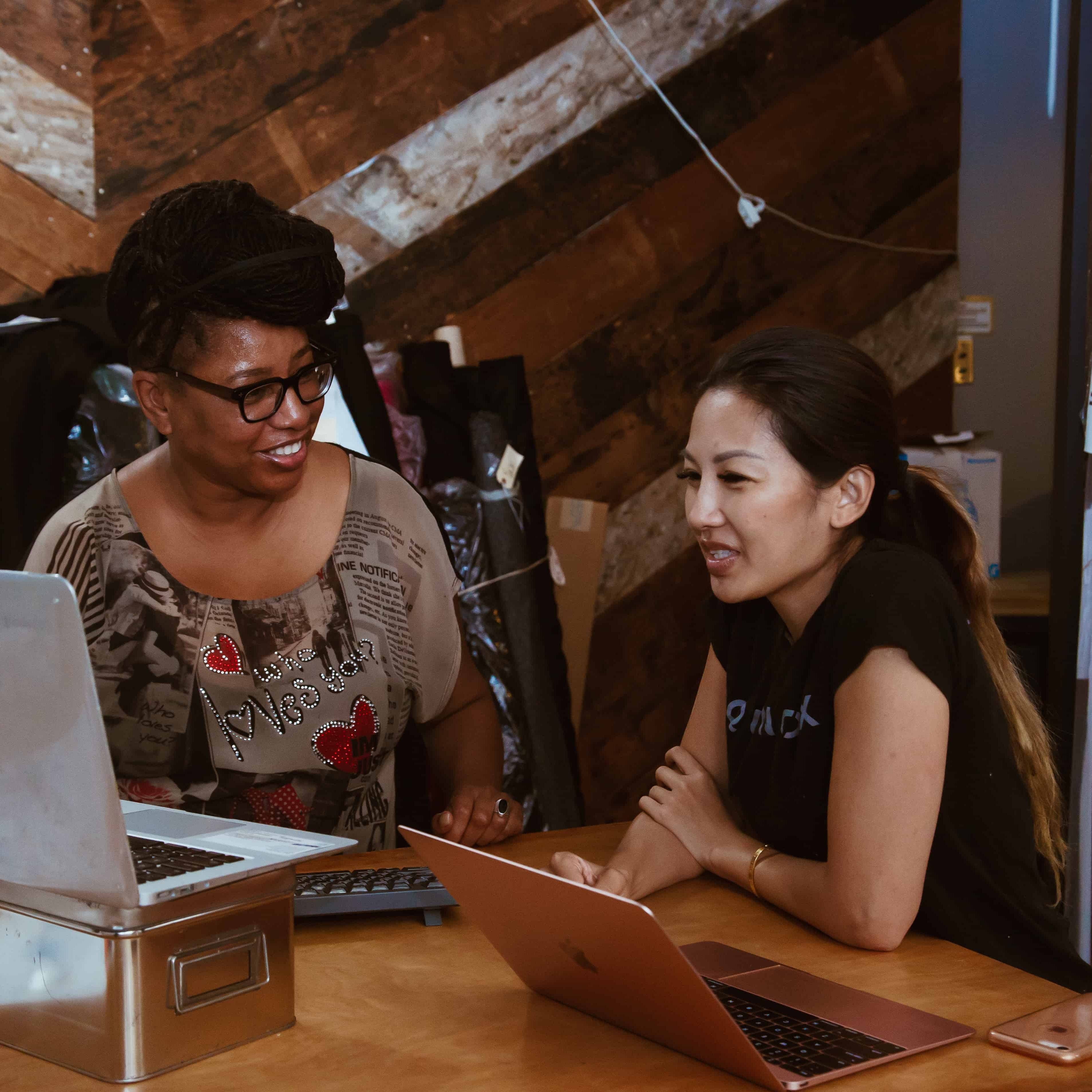 Two people discussing work on laptops