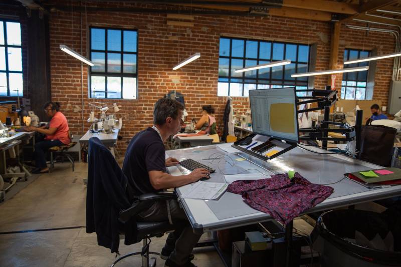 Manufacturing working on laptop designing clothing