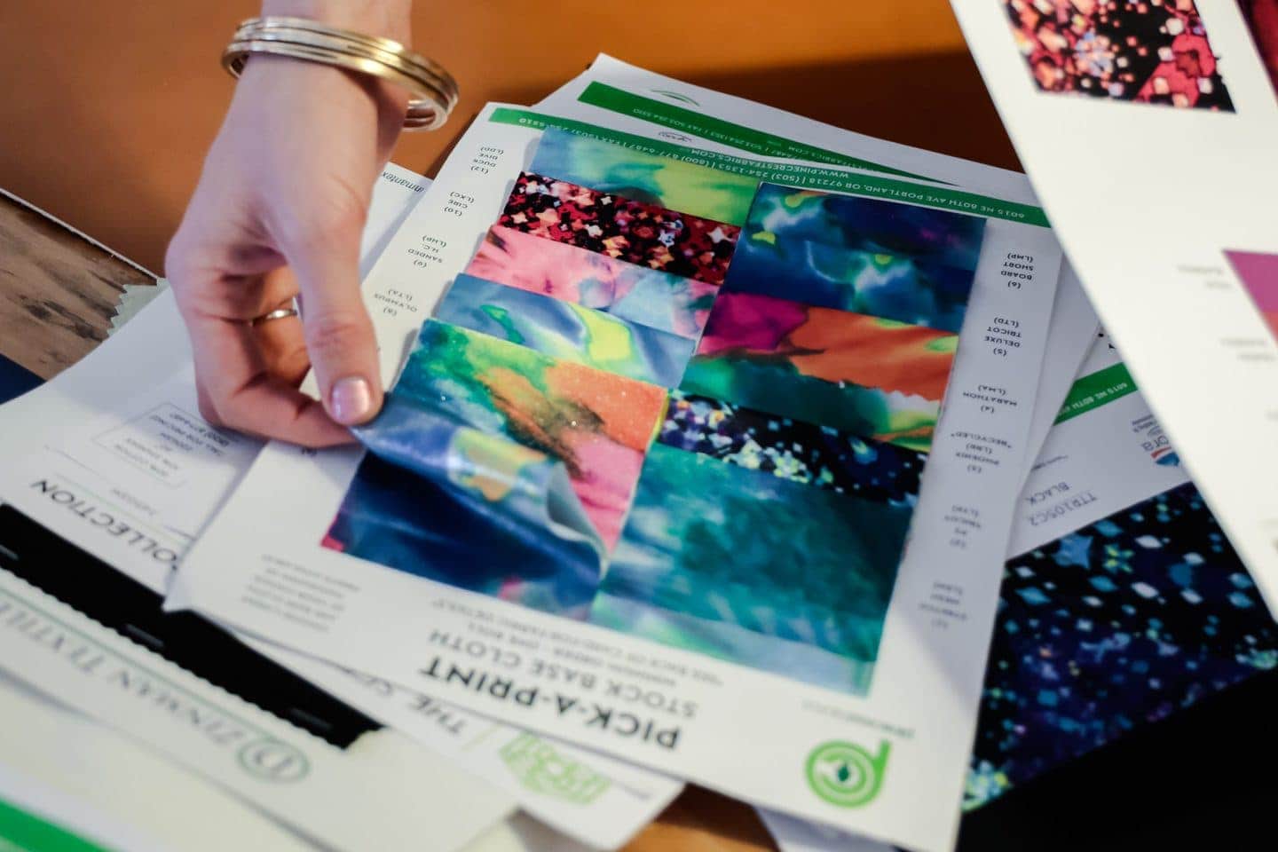 fashion production: Woman looking through a variety of sample printed fabric designs