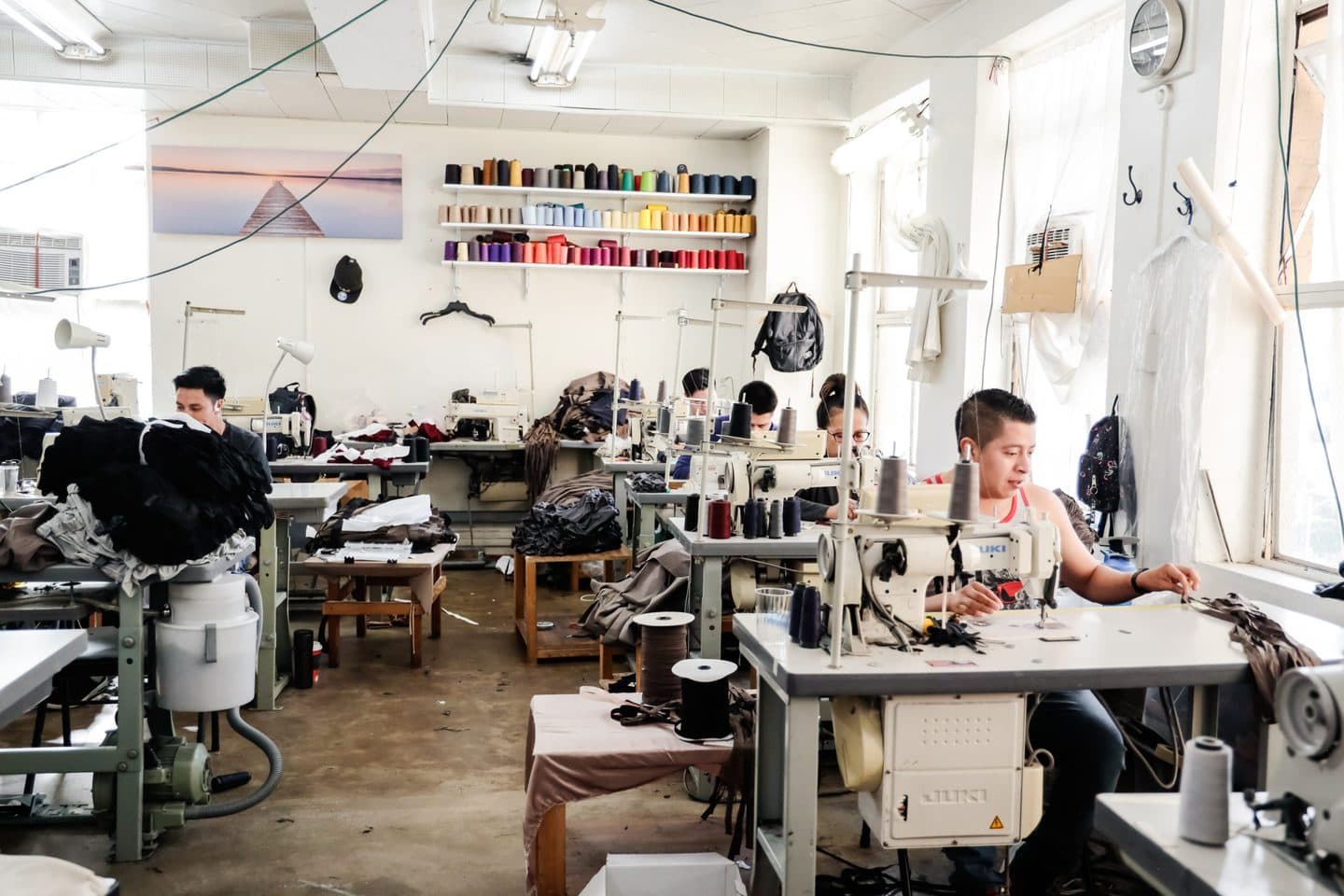 Interior shot of a clothing manufacturing studio with tailors and seamstresses at sewing machines