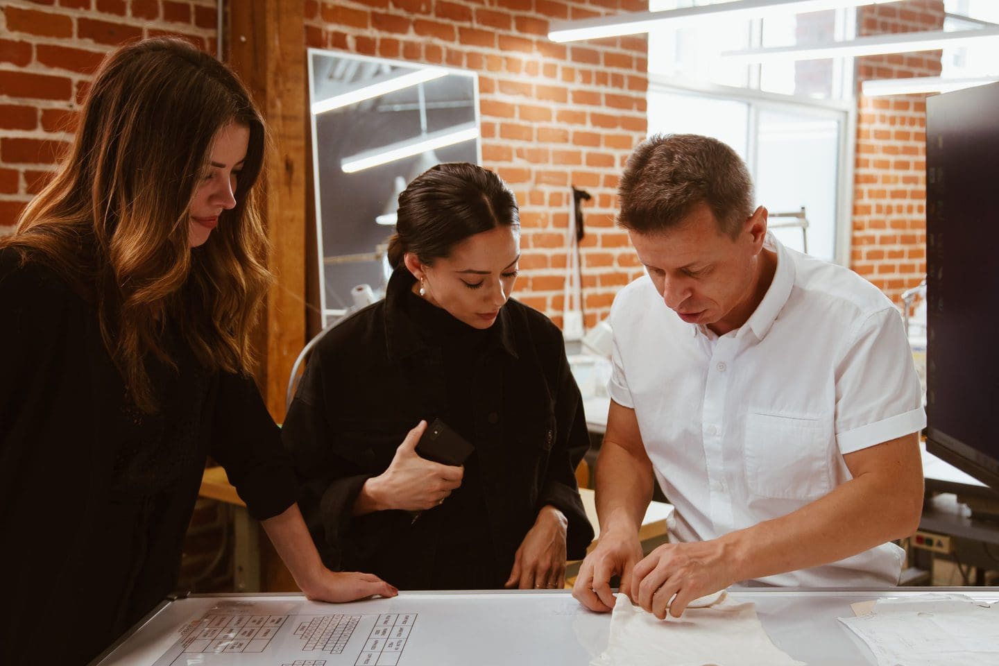 A pattern maker in Los Angeles explaining a fashion decision to two independent fashion designers