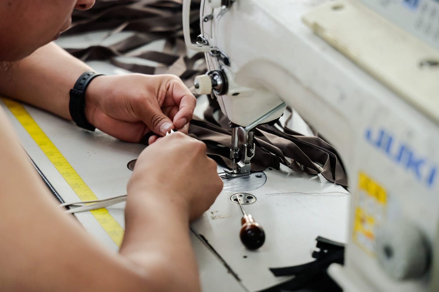 Closeup of a sustainable clothing manufacturer working on fabric at a sewing machine