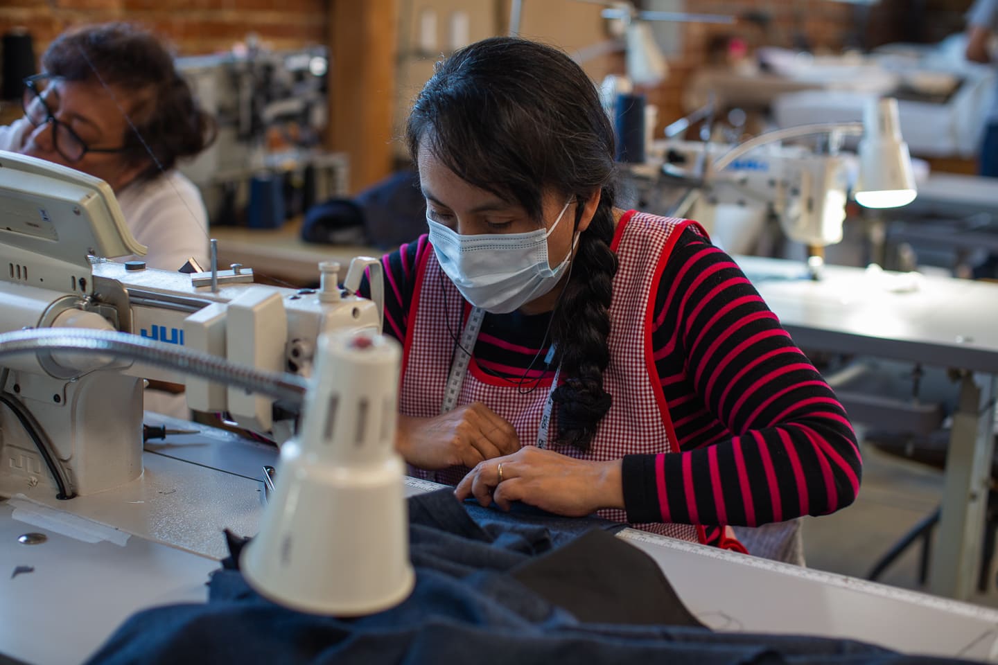 A masked Los Angeles seamstress working on a low minumum order quantity clothing order
