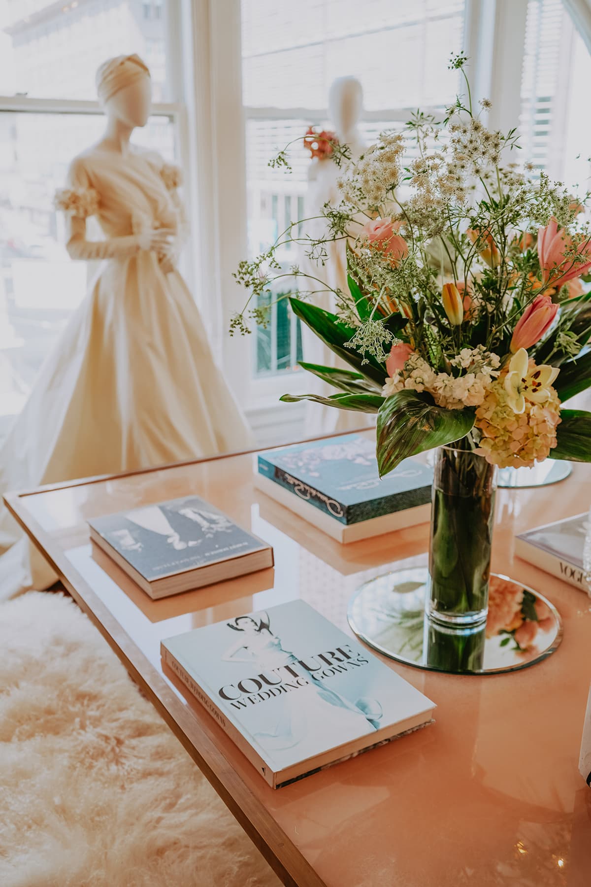 Table with books in the foreground and bridal wear in the background at the San Francisco clothing design studio