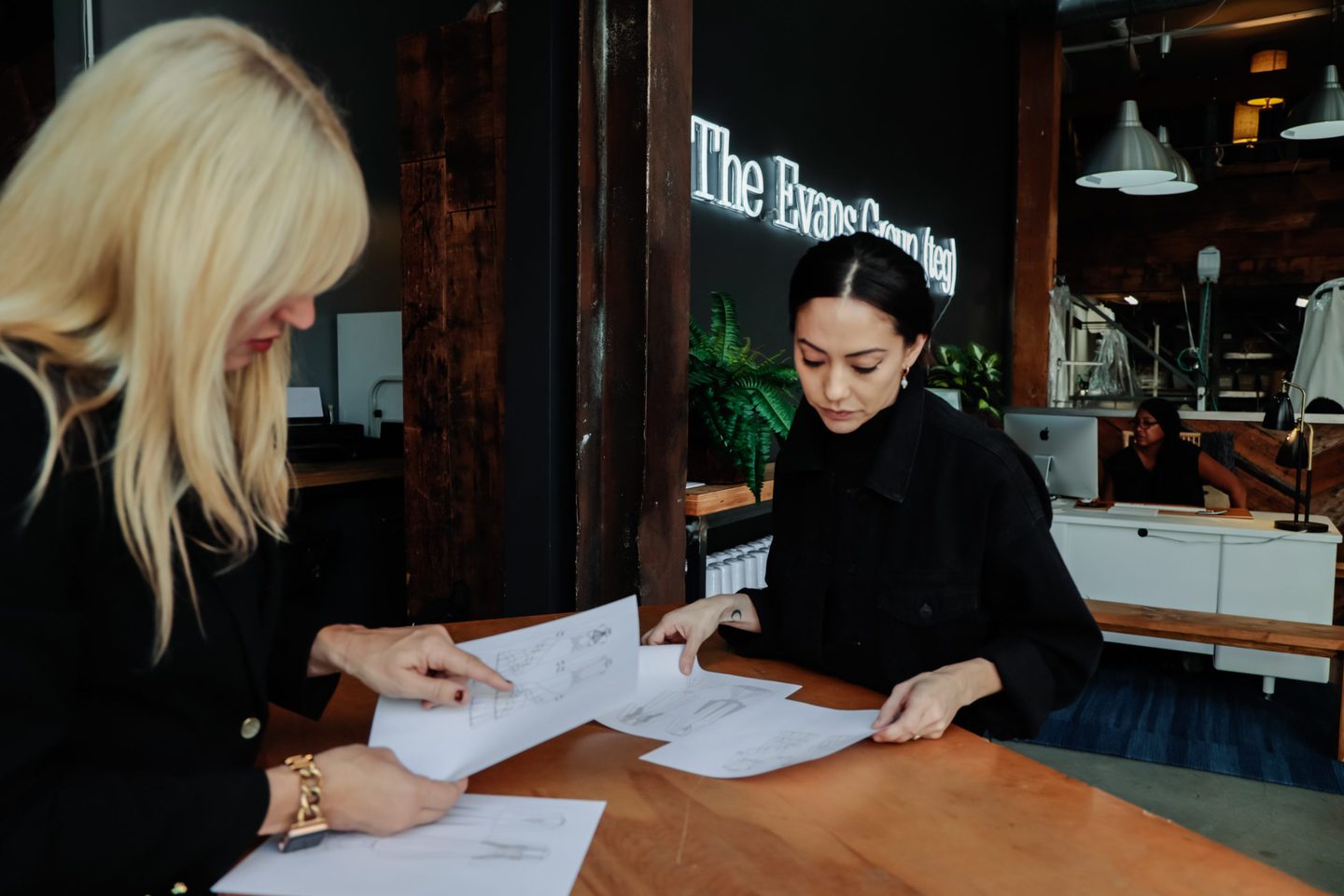 Jennifer Evans and a fashion designer examining fashion sketches