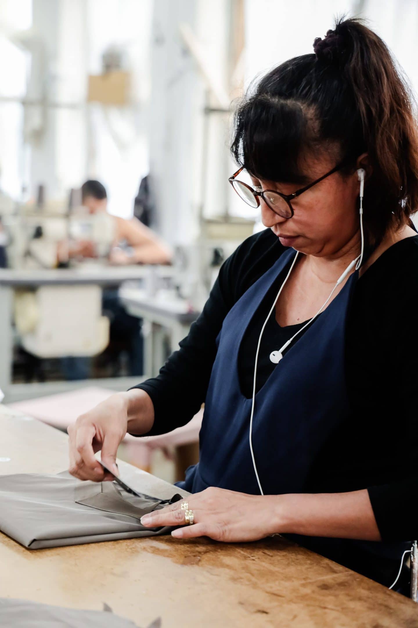 Los Angeles clothing manufacturer examining beige fabric in studio