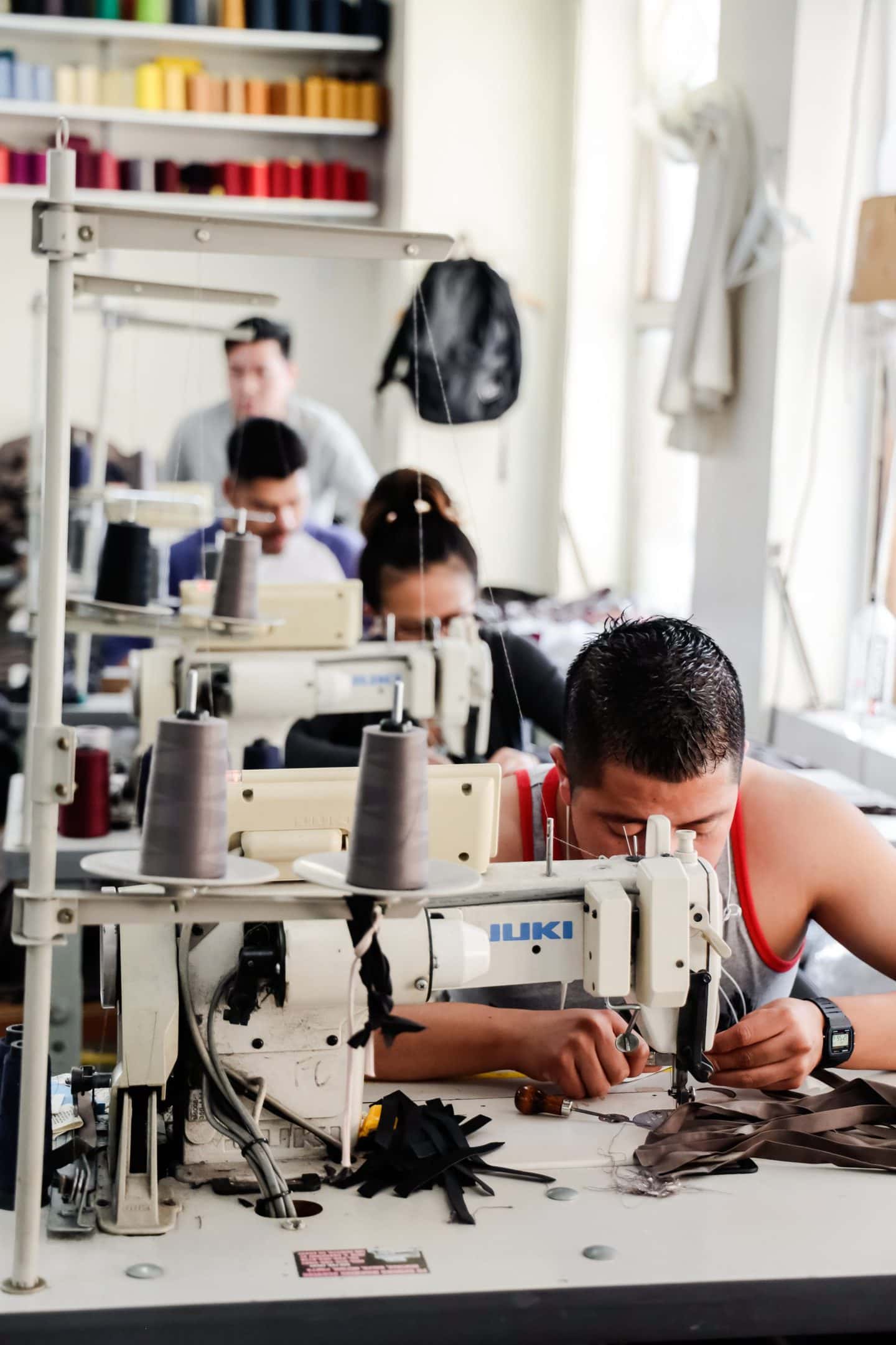 four textile workers at sewing machine at a Los Angeles clothing manufacturing studio