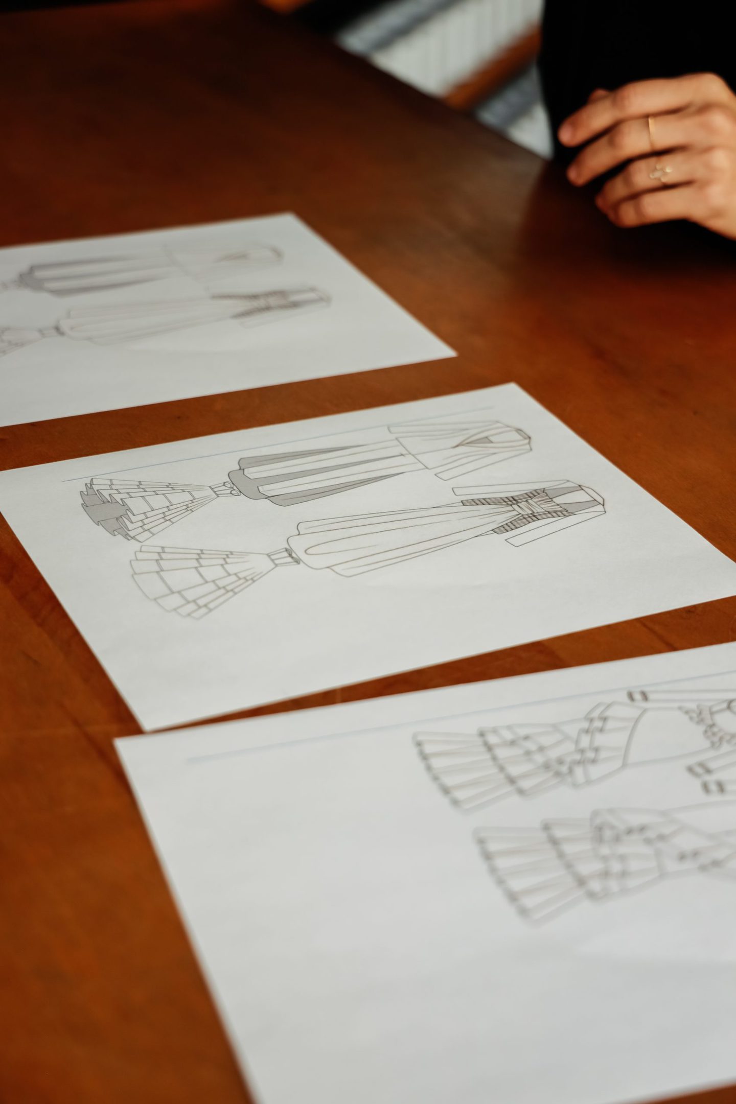 three fashion sketches on a wooden table