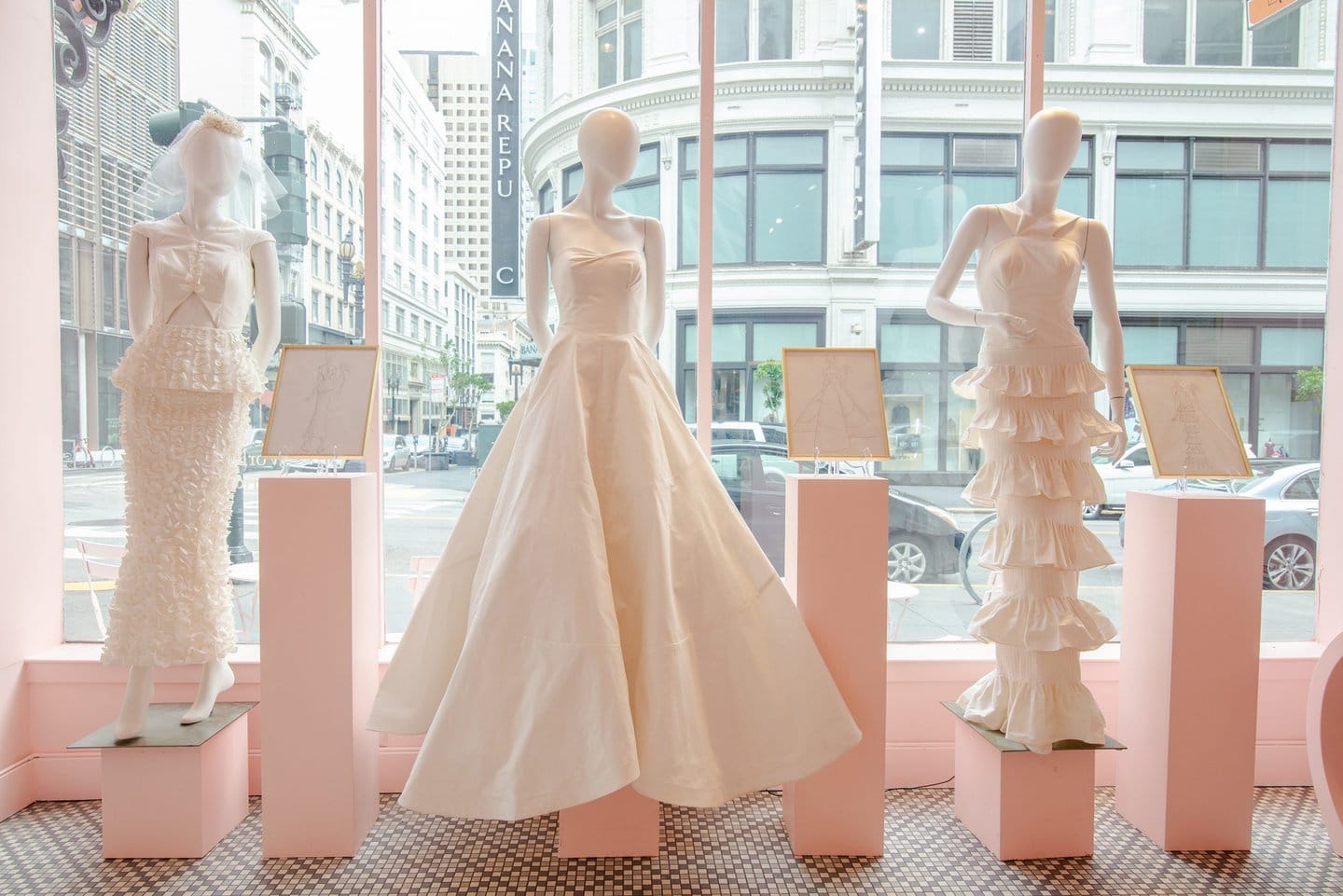 three mannequins wearing werdding gowns in a storefront window